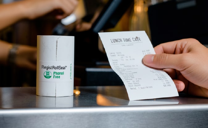 NCCO thermal paper rolls at POS Counter Customer receiving a phenol-free thermal receipt printed on NCCO thermal paper rolls