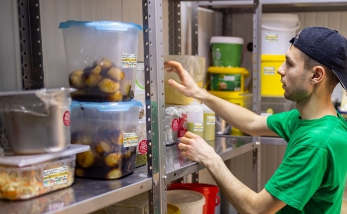NCCO thermal paper rolls at POS Counter Foodservice worker using food rotation labels on containers in a commercial kitchen storage area
