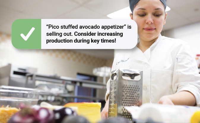 Chef in a commercial kitchen with a RightBytes operations management alert recommending increased production for a popular menu item